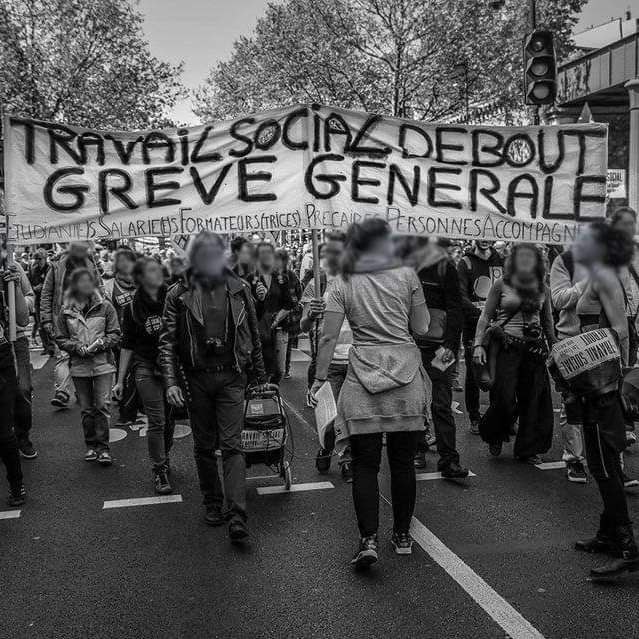 Photo de manif (crédit inconnu) : banderole :
"Travail social debout 
Grève générale 
Etudiants salariés formateurices précaires personnes accompagnées"