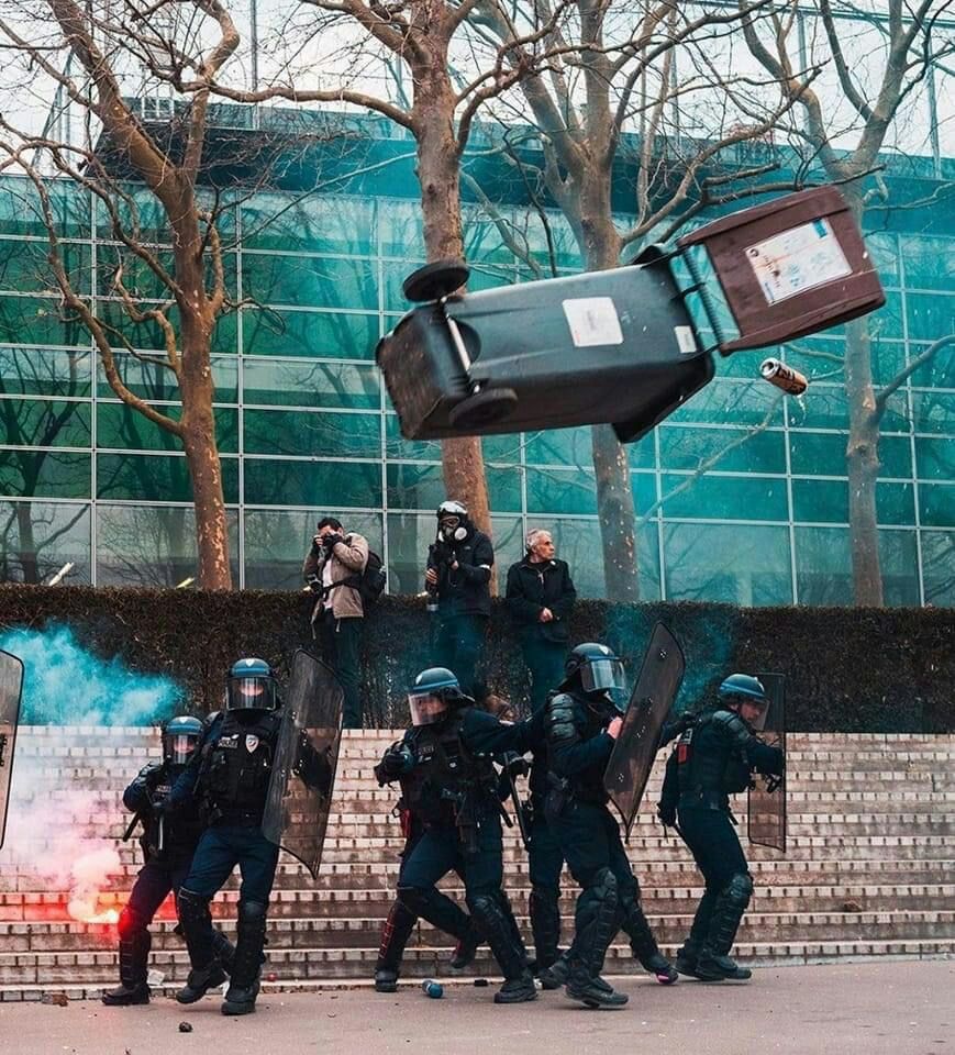 Photo de Benjamin Guillot Moueix. 
Poubelle volant au-dessus d'un groupe de flics lors d'une manif contre la réforme des retraites.
