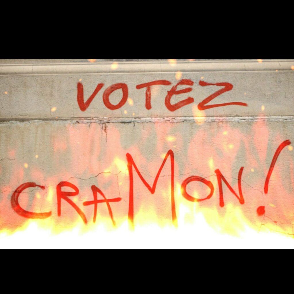 Tag sur un mur : "Votez Cramon !", des flammes ont été ajoutées dessous.