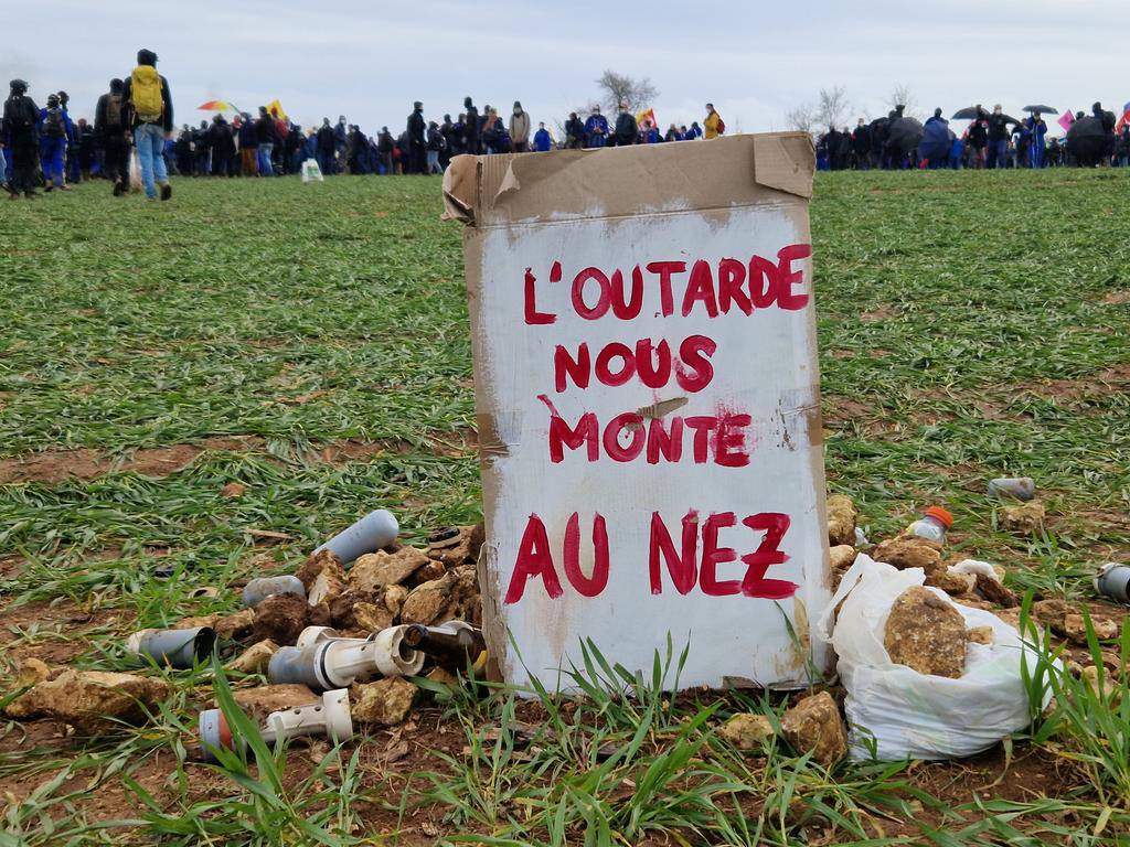 Photo crédit inconnu. Dans un champ à Sainte-Soline des restes de lacrymo et grenades ont été amassées, un panneau a été ajouté par les militants du groupe de l'Outarde sur lequel est noté : "L'outarde nous monte au nez"