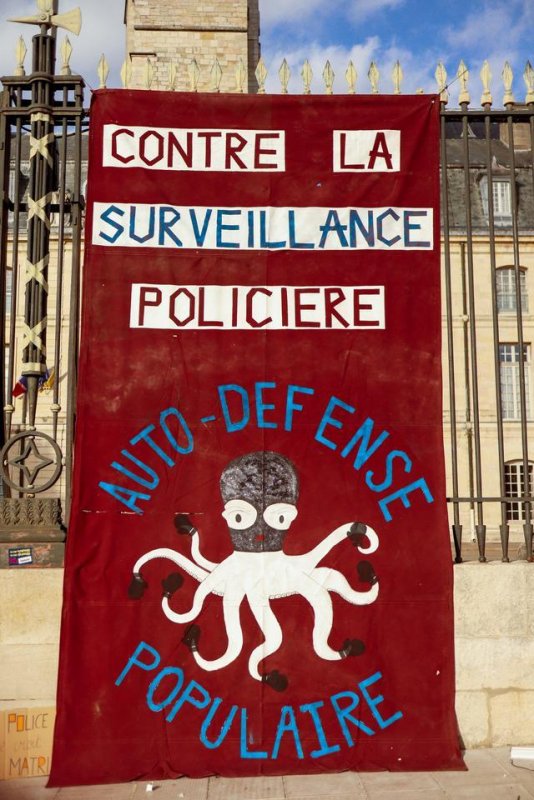 Photo de Dijoncter :
Pancarte accrochée sur les grilles d'une institution : "Contre la surveillance policière auto-défense populaire"