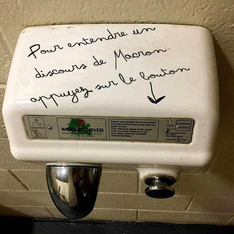 Photo (crédit inconnu) d’un sèche-mains dans des toilettes publics sur lequel il est écrit : « Pour entendre le discours de Macron appuyez sur le bouton ».