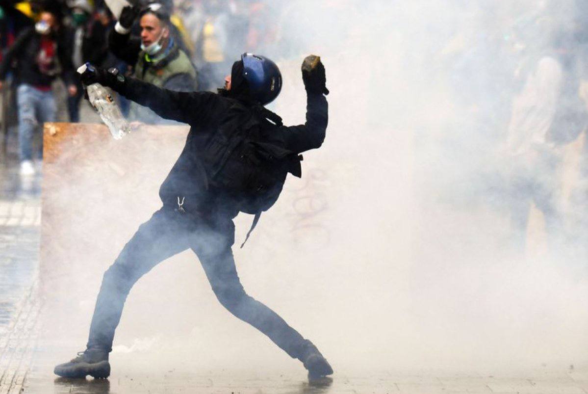 Photo (crédit inconnu) d'un manifestant au milieu des gaz lacrymo s'apprêtant à jeter une pierre.