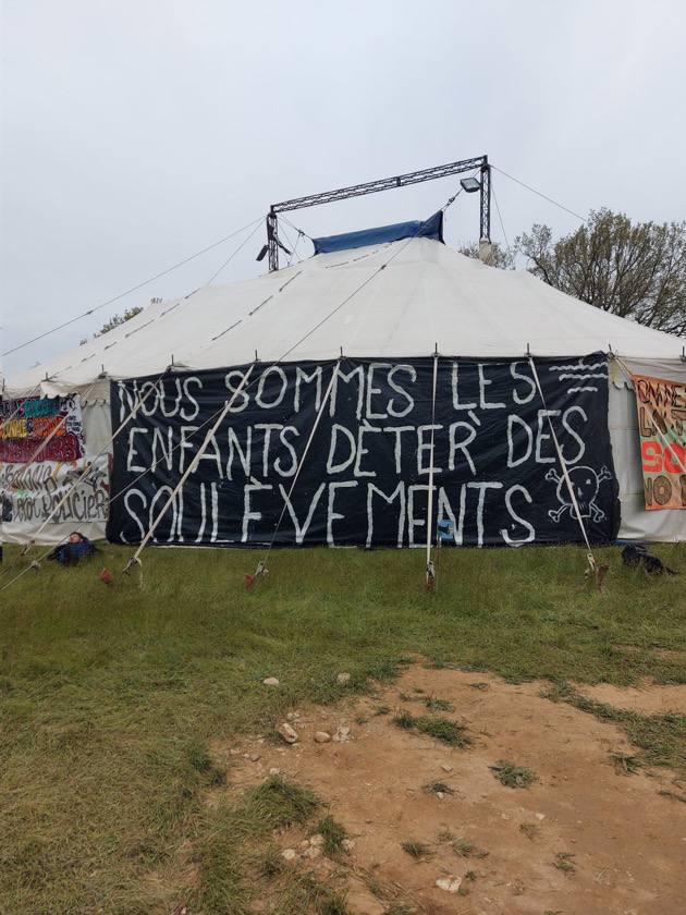 Photo de Radio Sauvage. Grande banderole sur un barnum : « Nous sommes les enfants deter des Soulèvements".