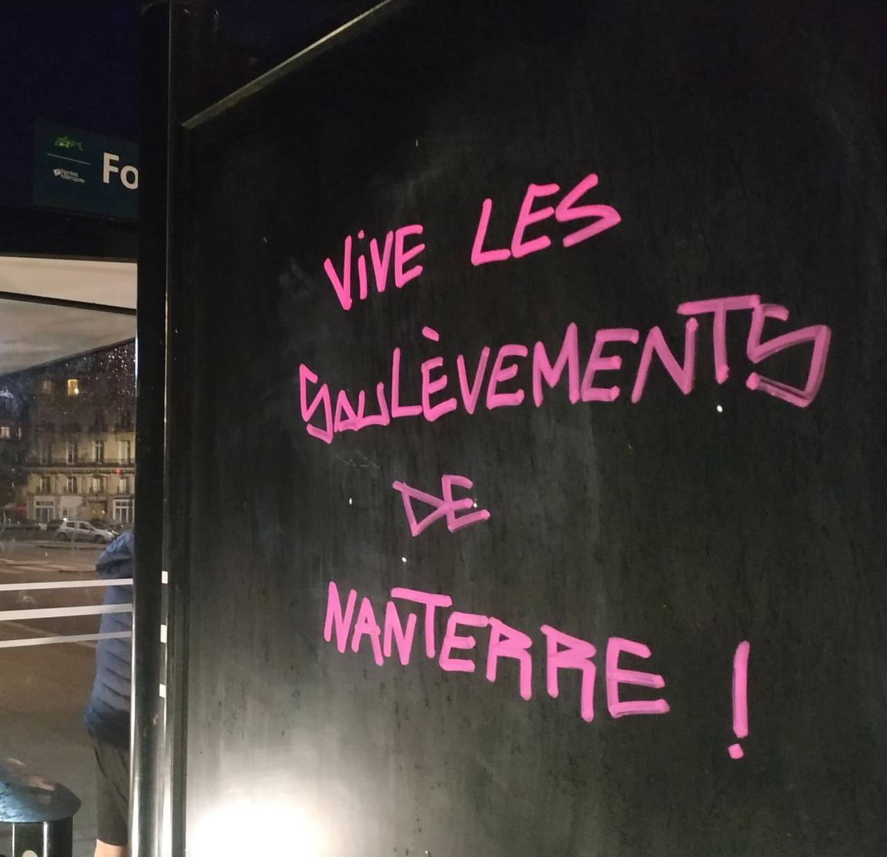 Photo de Contre-Attaque prise à Nantes. Tag rose sur un mur noir : "Vive les Soulèvements de Nanterre".