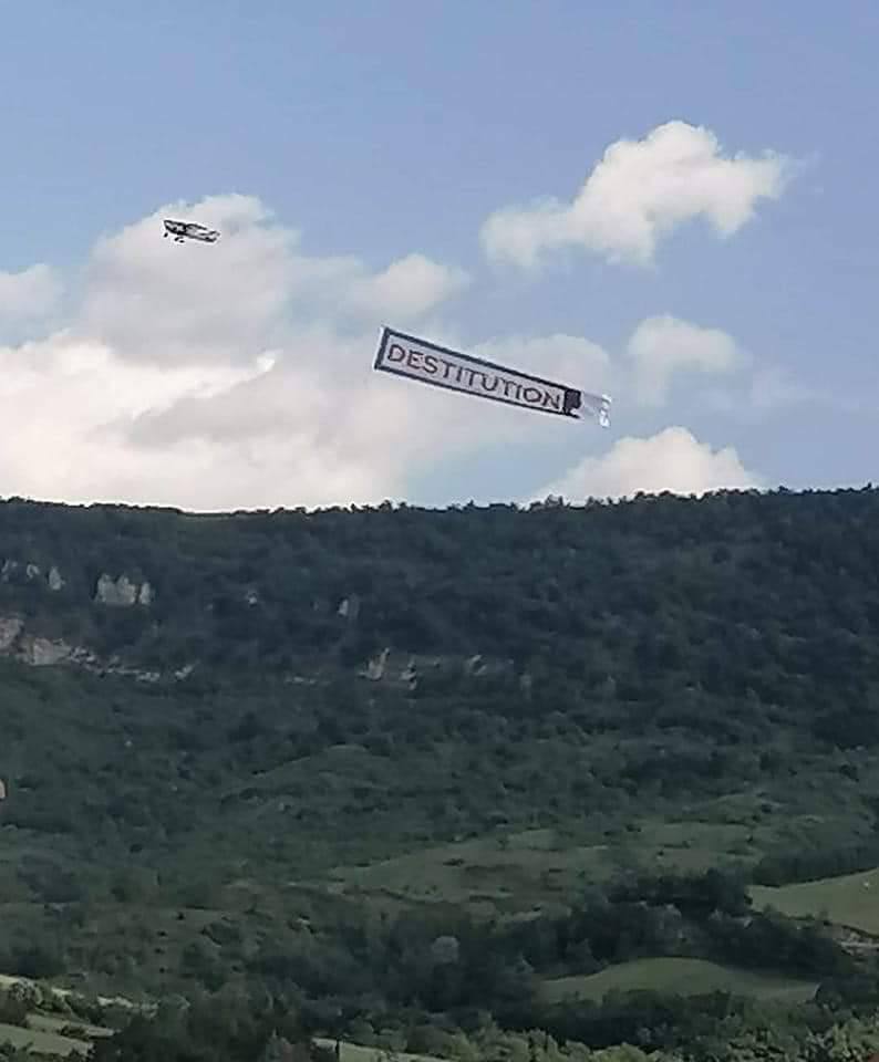 Photo via Sadi Bencherif. Avion en vol trainant derrière lui une banderole sur laquelle est marqué "DESTITUTION".