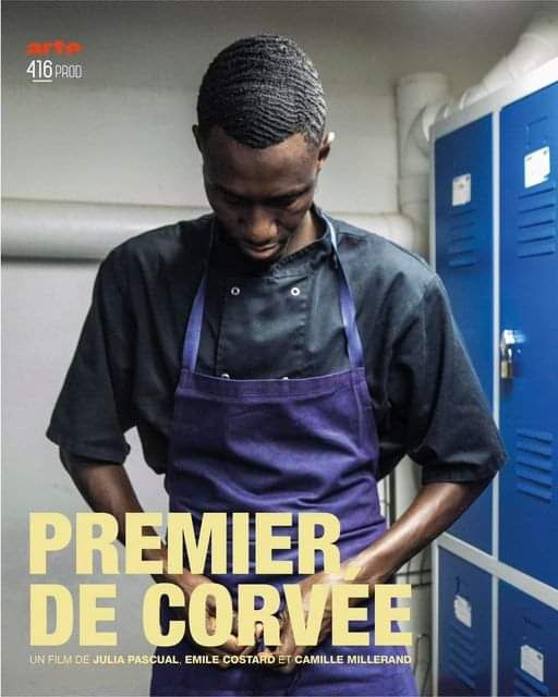 Affiche du documentaire "Premier de corvée". 
On voit un homme noir (Makan, personnage central du film) dans un vestiaire, il porte un uniforme noir et un tablier violet qu'il est en train de nouer. 