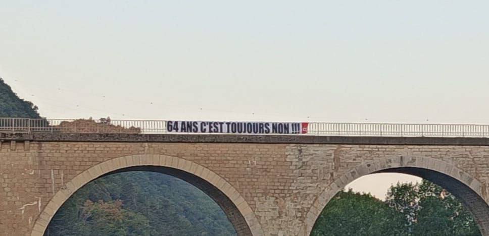 Photo crédit CGT montrant une grande banderole portant l'inscription "64 ans c'est toujours non"  installée sur le viaduc de Sisteron.