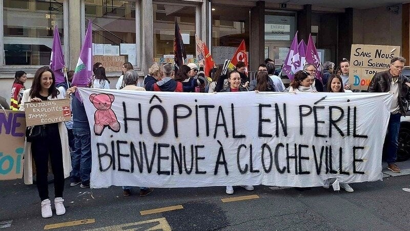 Photo crédit inconnu. Manifestation devant l'hôpital de Clocheville le 2 octobre. Banderole avec une nounours dessiné et ce texte : "Hôpital en péril.Bienvenue à Clocheville".