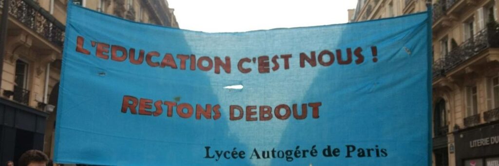Photo du LAP montrant une banderole sur laquelle il est écrit "L'éducation c'est nous. Lycée Autogéré de Paris".