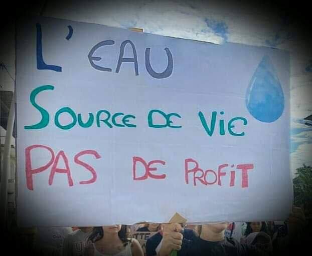 Photo d’une banderole «  L’eau source de vie pas de profit ».