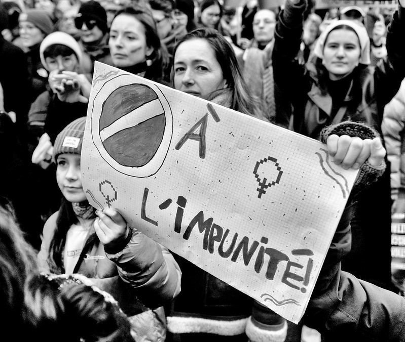 Photo en noir et blanc, crédit inconnu, prise pendant une manifestation féministe. Pancarte avec texte "Stop à l'impunité". 