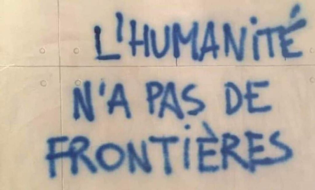 Alt : sur un mur est écrit en lettres majuscules, l’Humanité n'a pas de frontières