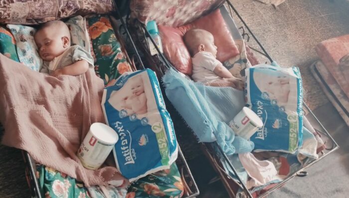 Photo bébés qui dorment dans des lits avec un paquet de couches et un pot de lait